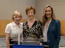 Three women standing next to a podium.